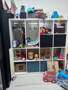 A photo of a modified Kallax unit from IKEA. The top 4 shelves on the left have been removed to create a wardrobe area.